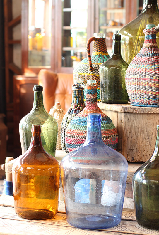 בקבוקי הזכוכית הגדולים נופחו בעבודת יד אצל הנפח של הכפר ושימשו לאיחסון היין המקומי לאחר השהייה בחבית